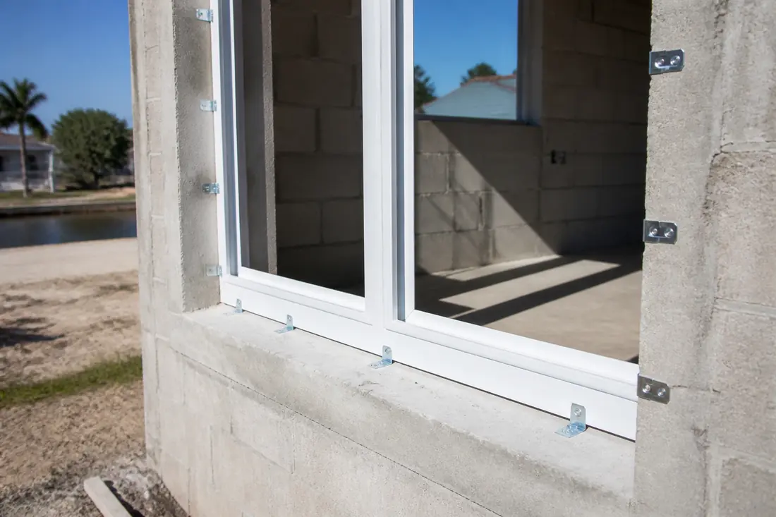An impact window frame being anchored into a concrete block opening
