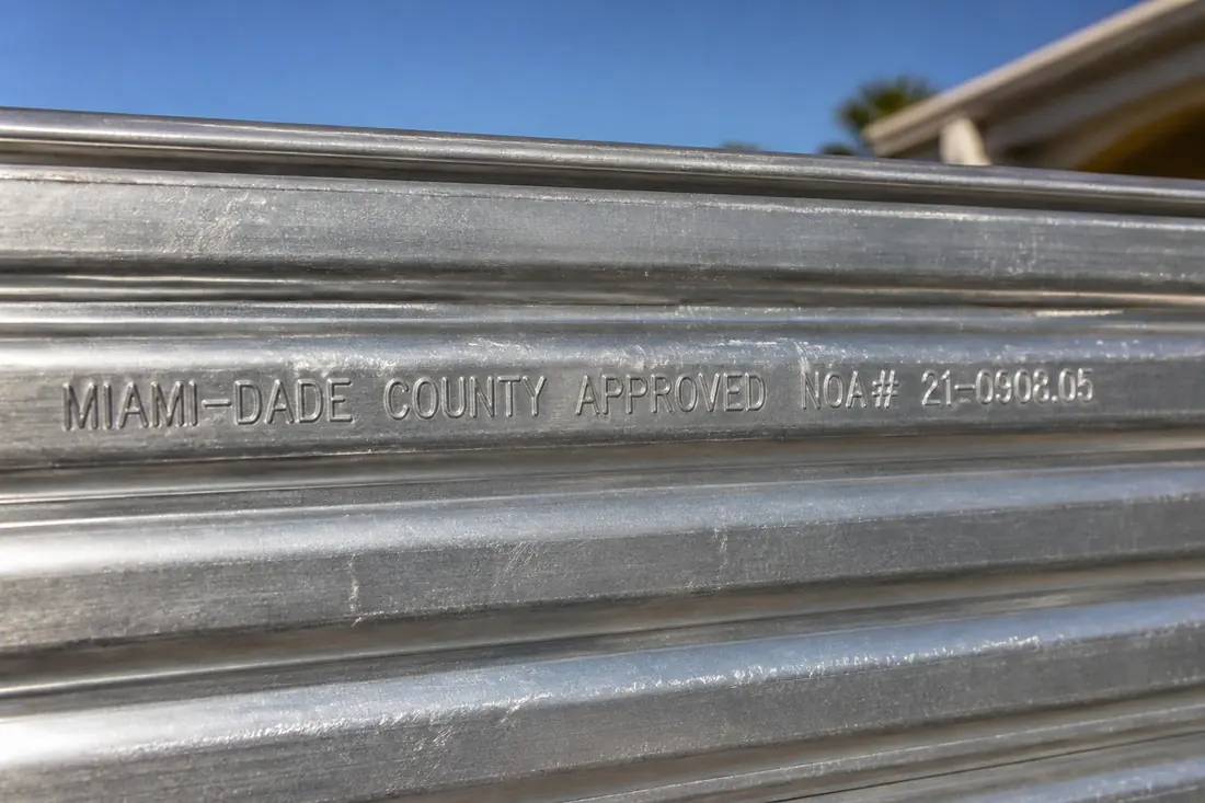 An embossed product approval label stamped into the face of an aluminum storm panel