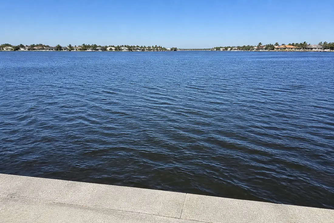Flat open water running away from a seawall to the far shore