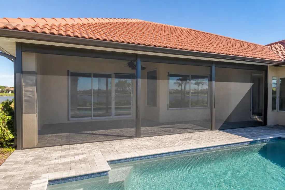 A screened lanai under an existing roof with the glazed wall separating it from the house