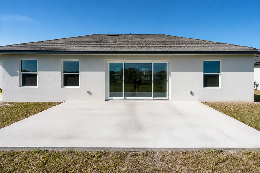 The rear elevation of a house showing a sliding glass door and several windows together