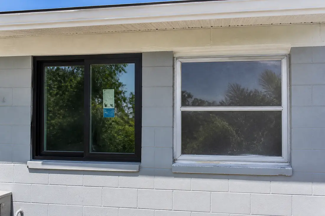A newly installed window beside an original aluminum one in the same wall